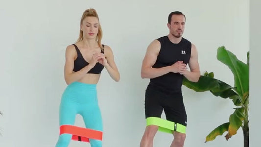Kadın ve erkek direnç bandı ile monster walk egzersizi yapıyor | Man and woman performing resistance band monster walk exercise.